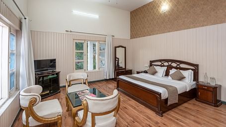 Spacious and bright guest room at DLS Tehri Club Resort with a king size bed and a seating area.